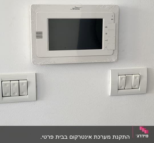 אינטרקום עם מסך ולחצנים על קיר לבן